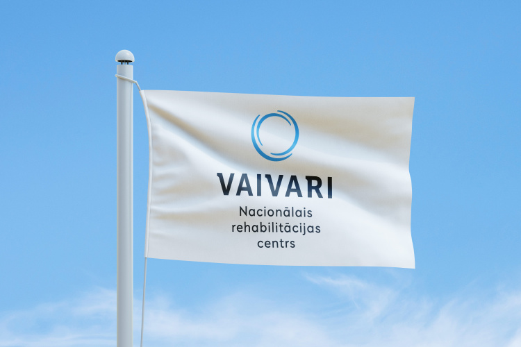 Zilā debesu fona priekšā, kurā redzami plāni mākoņi, plīvo balts karogs ar zilu apaļu logotipu un uzrakstu „VAIVARI Nacionālais rehabilitācijas centrs”.