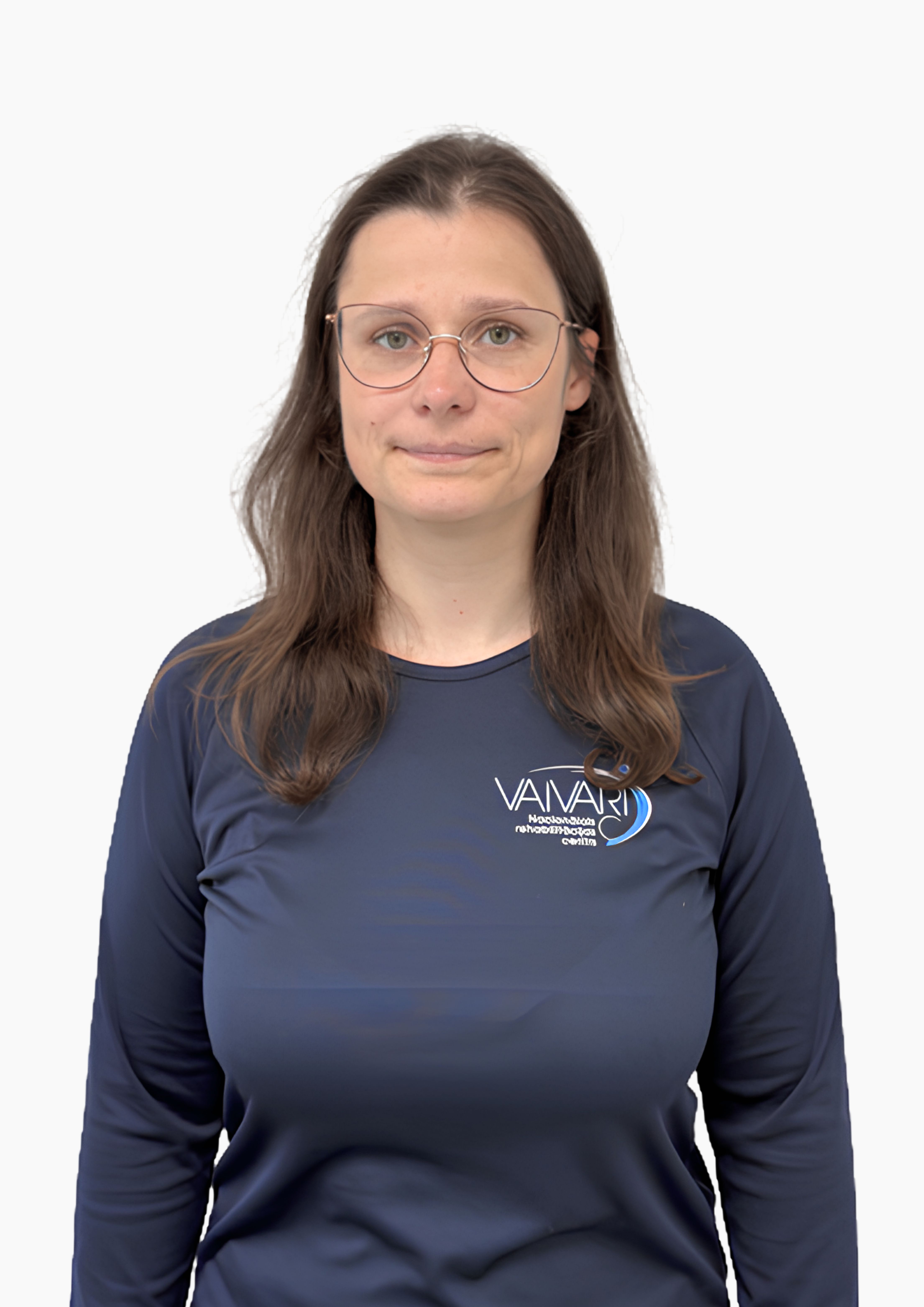Sieviete ar gariem brūniem matiem un brillēm, tērpusies tumši zilā krekliņā ar „Vaivari“ logotipu, stāv priekšā vienkāršam baltam fonam, skatoties kamerā ar neitrālu sejas izteiksmi.